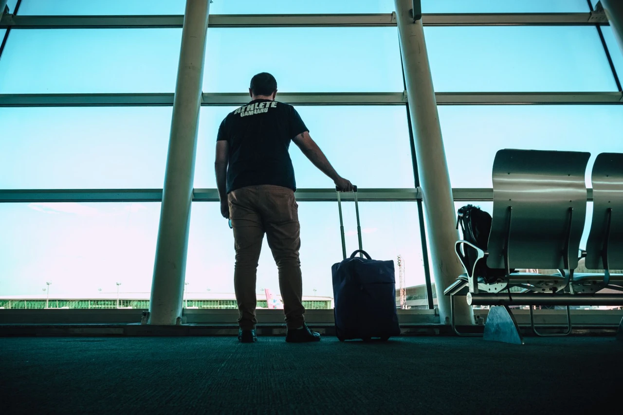 Traveler measuring a carry-on suitcase against an airline gate sizer before boarding